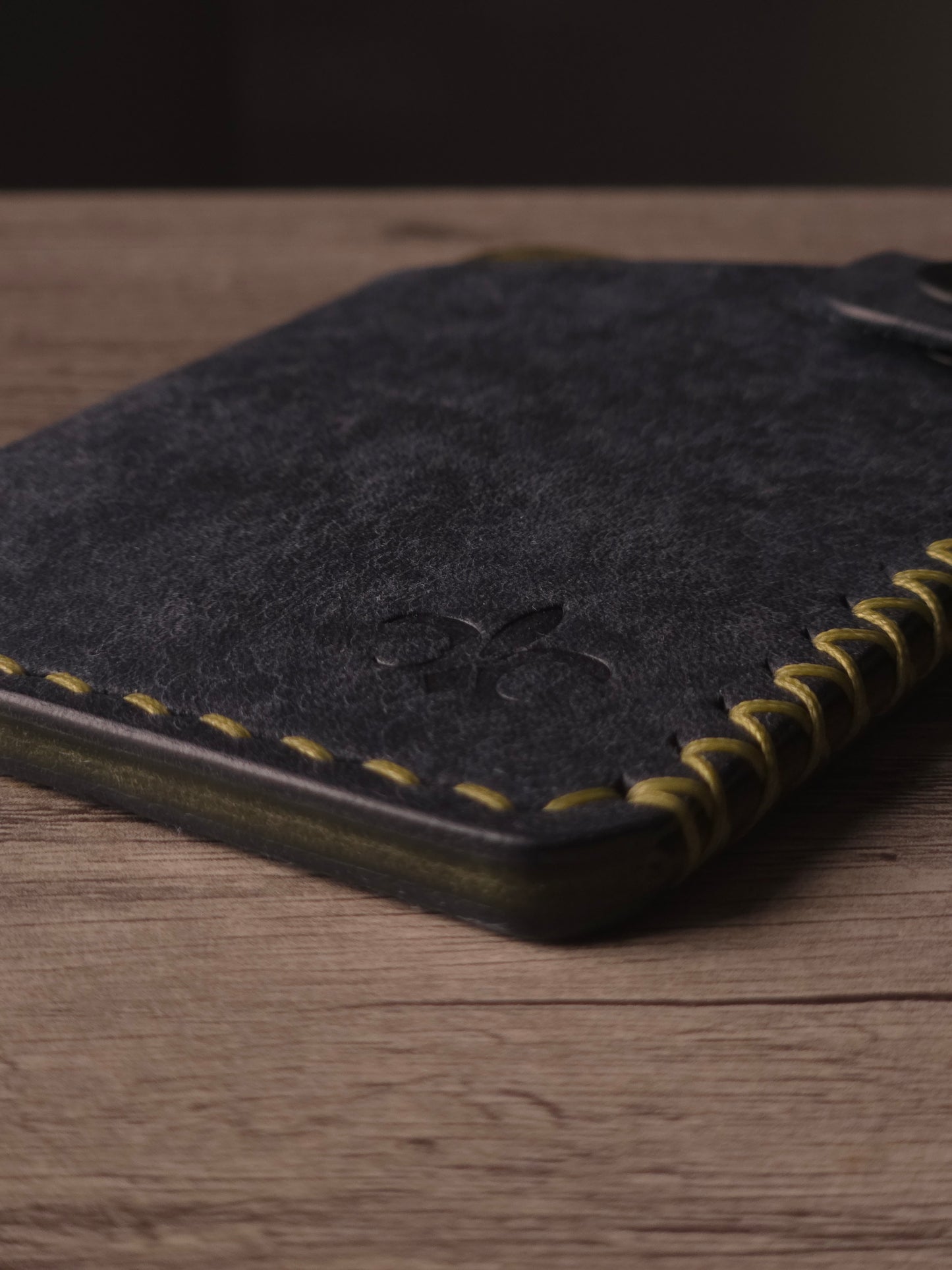 Hand saddle stitching detail on a handcrafted leather wallet. colors are navy & olive
