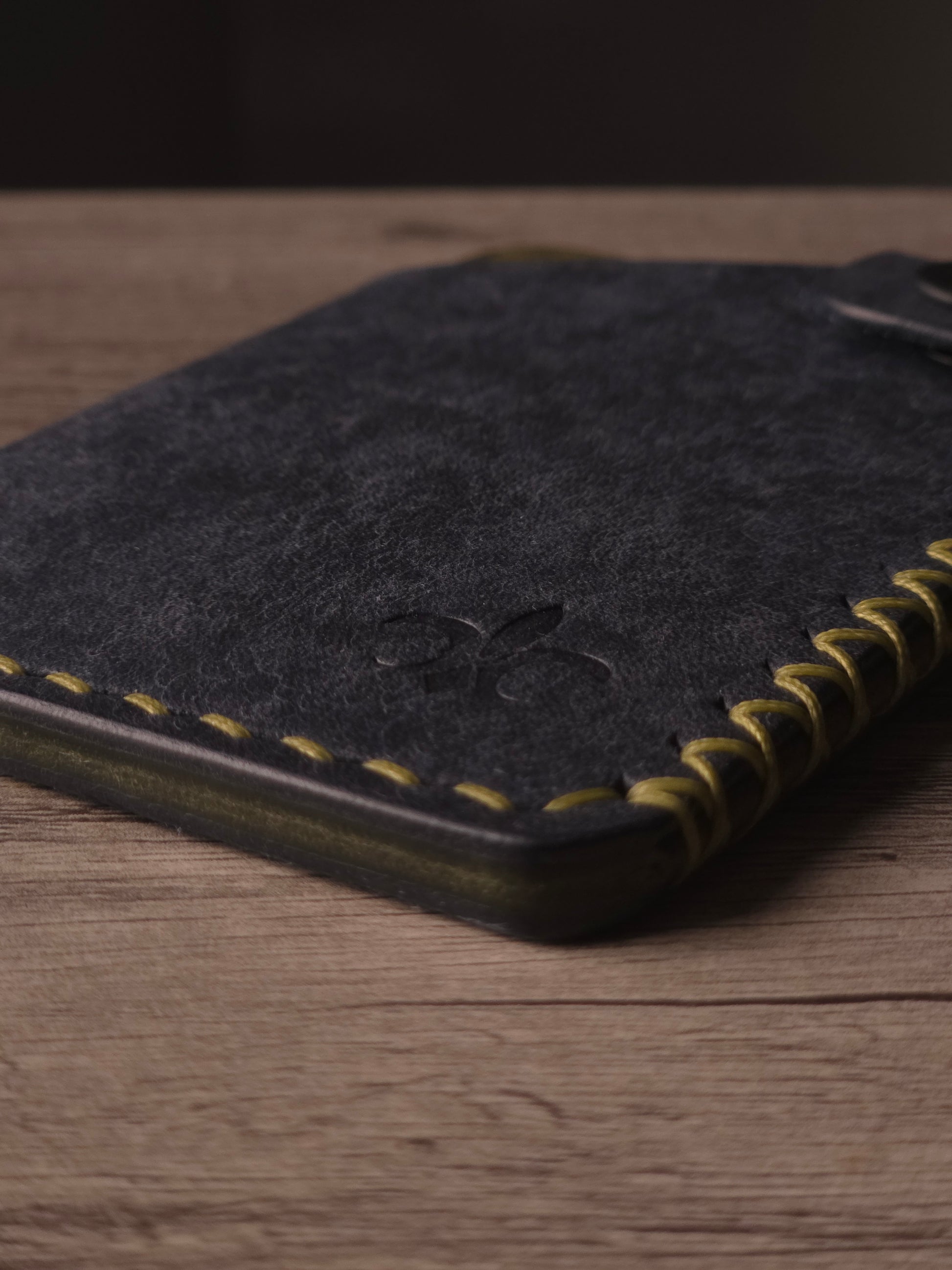 Hand saddle stitching detail on a handcrafted leather wallet. colors are navy & olive
