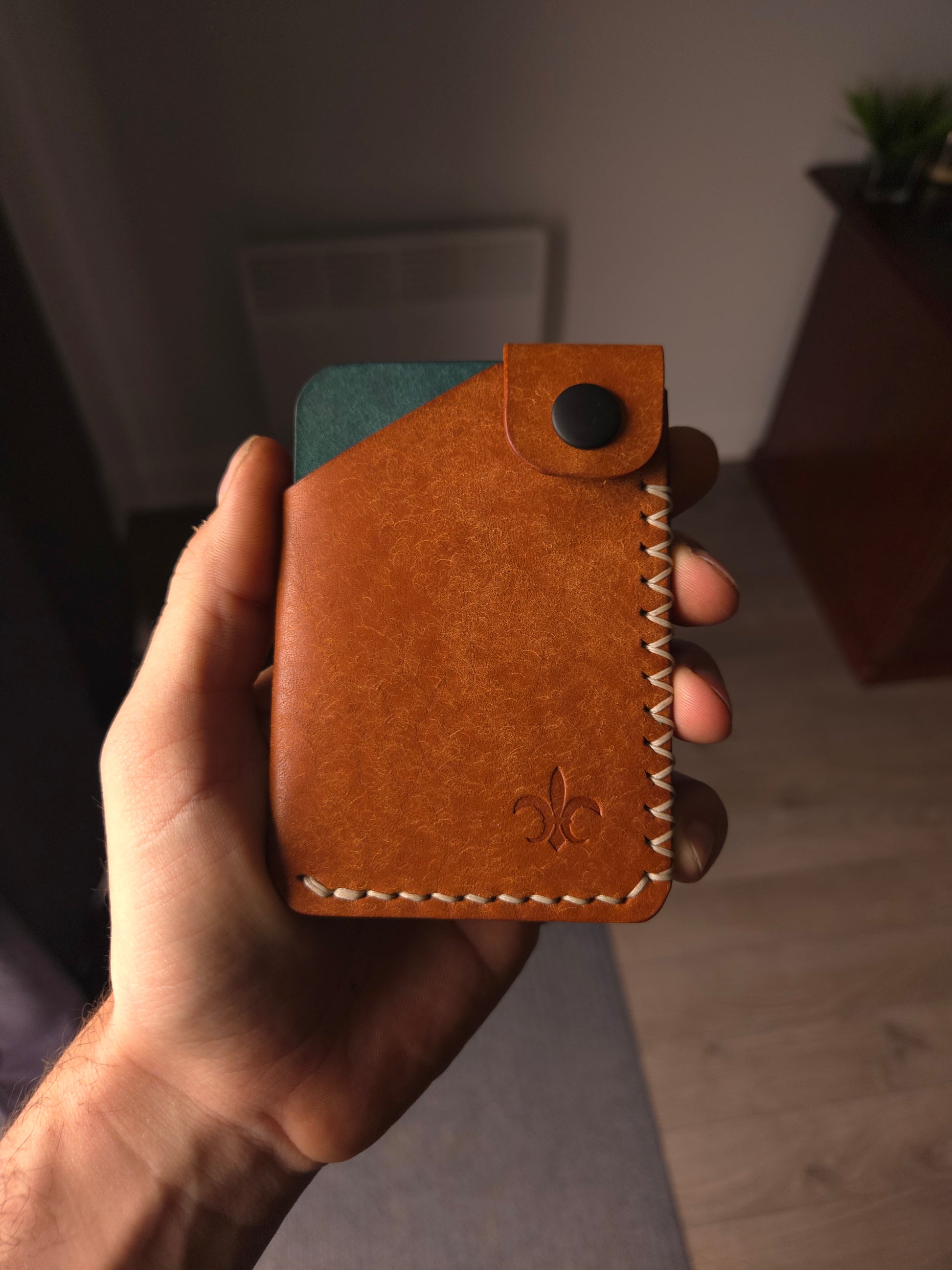 Le Patron leather wallet held in hand showing size and profile.
colors are cognac & aqua.