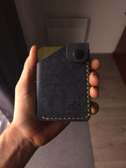 Le Patron leather wallet held in hand showing size and profile. the colors are navy & olive.