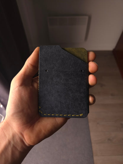 Le Patron leather wallet held in hand showing size and back card access. colors are navy & olive.