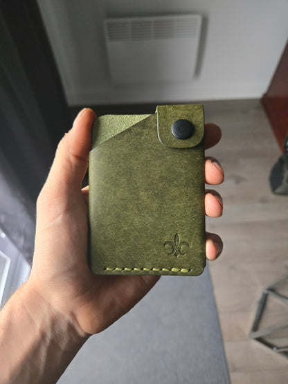 Le Compact leather wallet held in hand showing size and profile.
color is Olive.