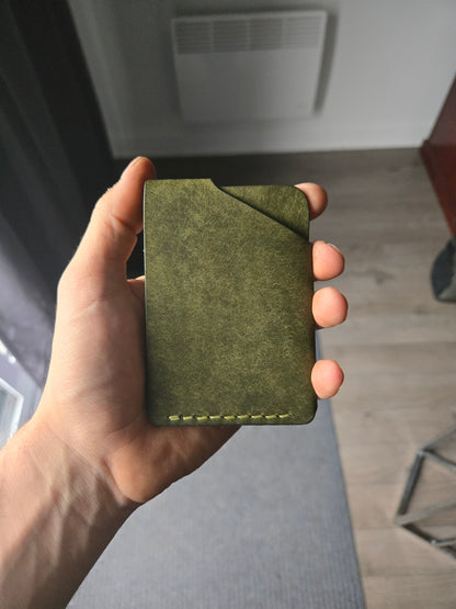 Le Compact leather wallet held in hand showing size and back profile. color is Olive.
